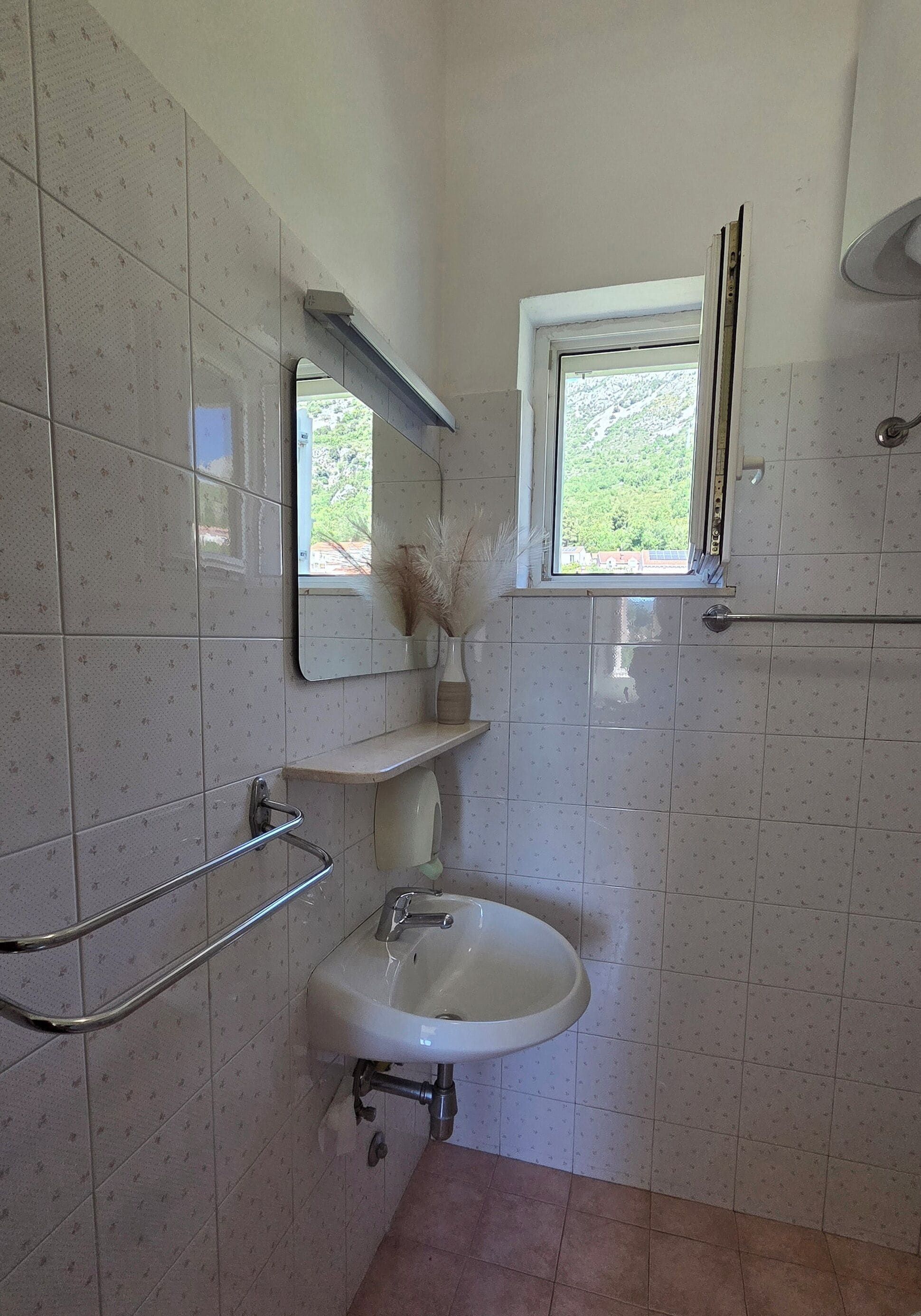 Ein Badezimmer mit Waschbecken, Spiegel, Fenster und Handtuchhalter.