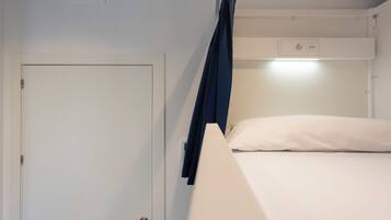 Un lit simple avec un matelas blanc et un rideau bleu foncé.