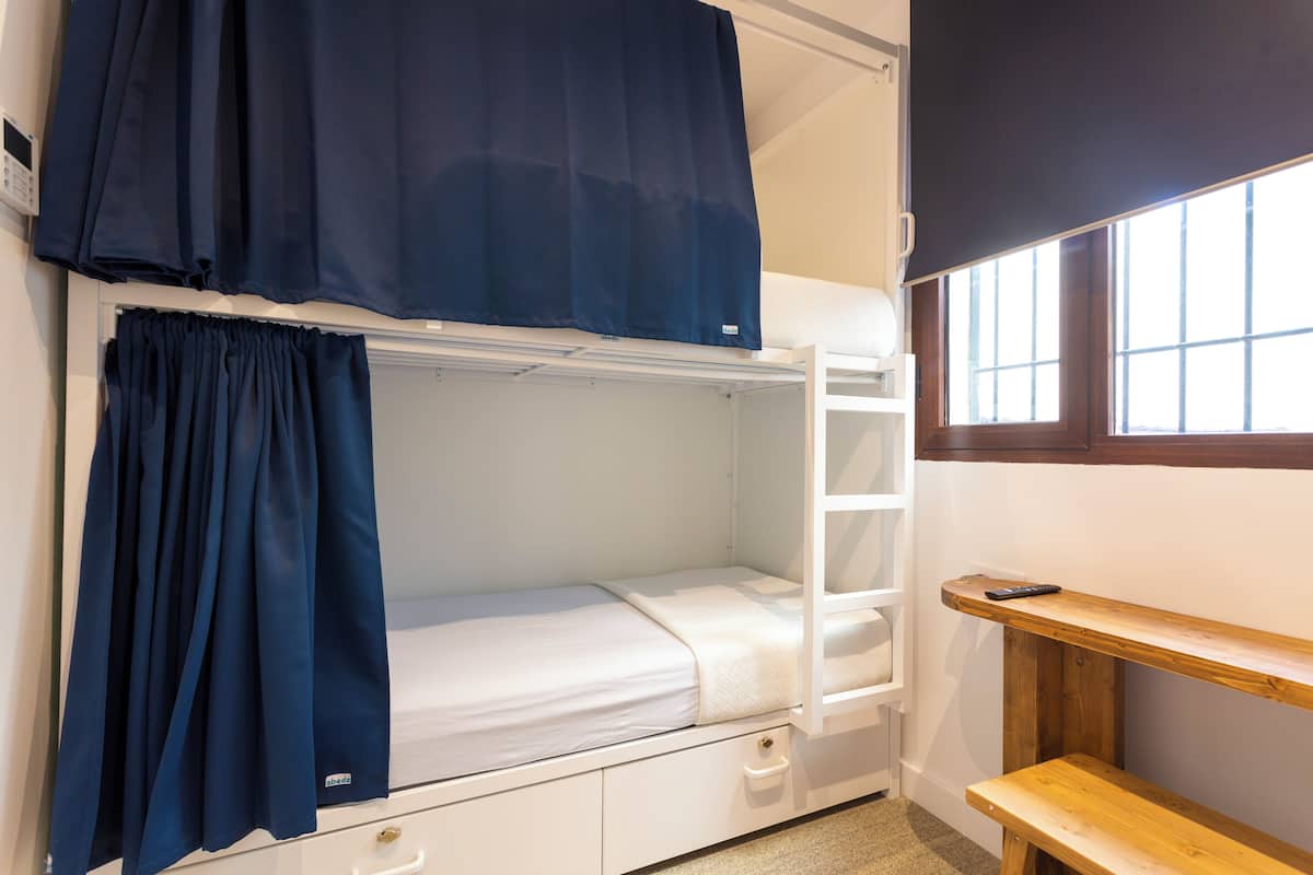 A bunk bed room with a desk and a window.