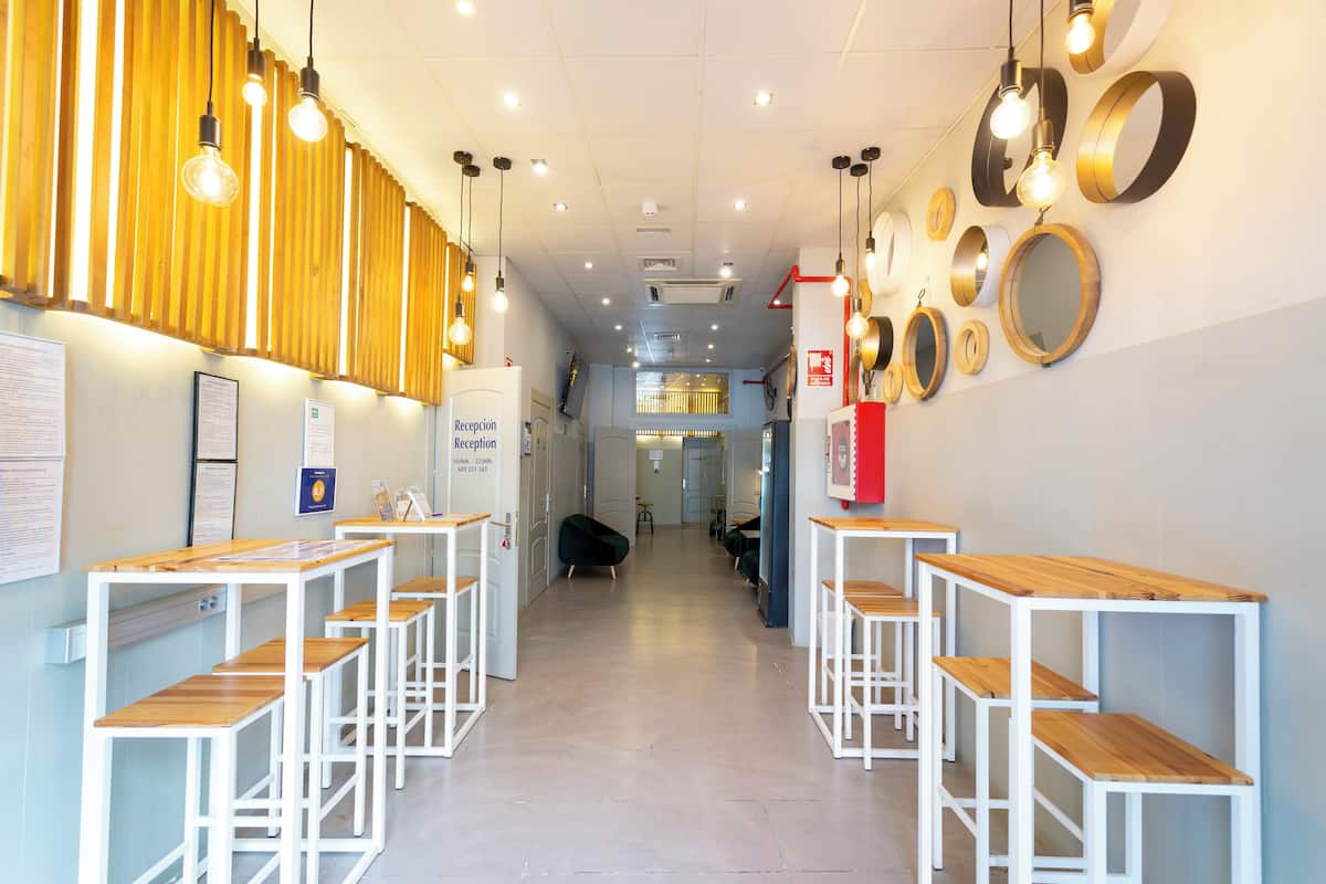 A reception area with wooden tables and benches, a reception desk, and a wall with circular mirrors.