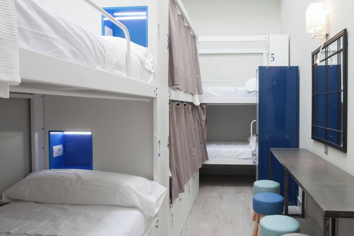 A dormitory room with bunk beds, a desk, and a blue cabinet.