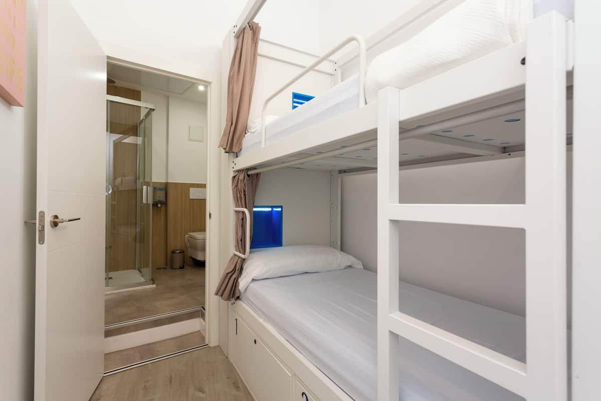 A bunk bed room with a shower area and a door leading to a bathroom.
