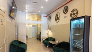 A hotel lobby with green seating, a vending machine, and a clock on the wall. - Málaga Stop Hostel (Málaga)