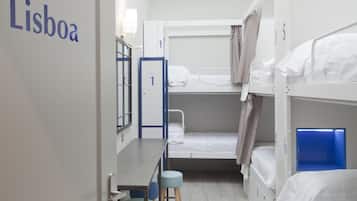 A hostel room with bunk beds, a desk, and a chair.