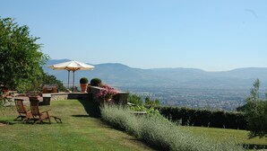 A patio with a table and chairs, a large umbrella, and a view of distant mountains. - Tenuta le Viiste (Scandicci)