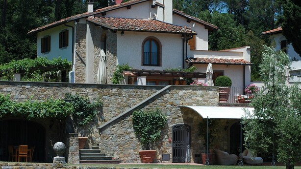 A two-story house with a stone facade, a swimming pool, and a patio area with outdoor furniture. - Tenuta le Viiste (Scandicci)