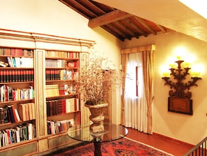 Une bibliothèque avec des étagères, une table en verre et une plante décorative.