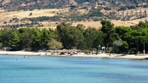 Un paysage côtier avec une plage, une eau claire et, en arrière-plan, des collines.