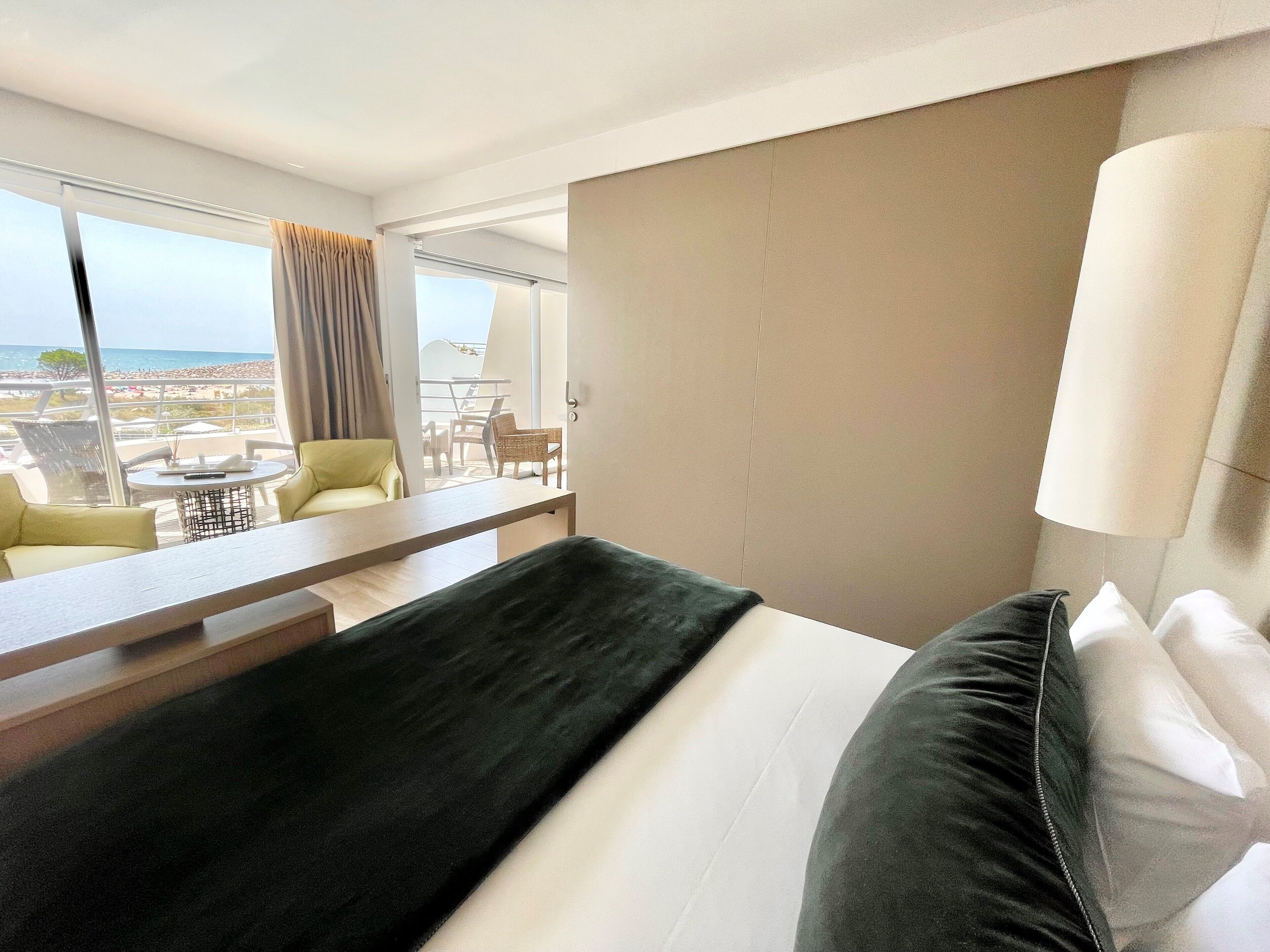 Een hotelkamer met een groot bed, een bureau en uitzicht op het strand en de oceaan.