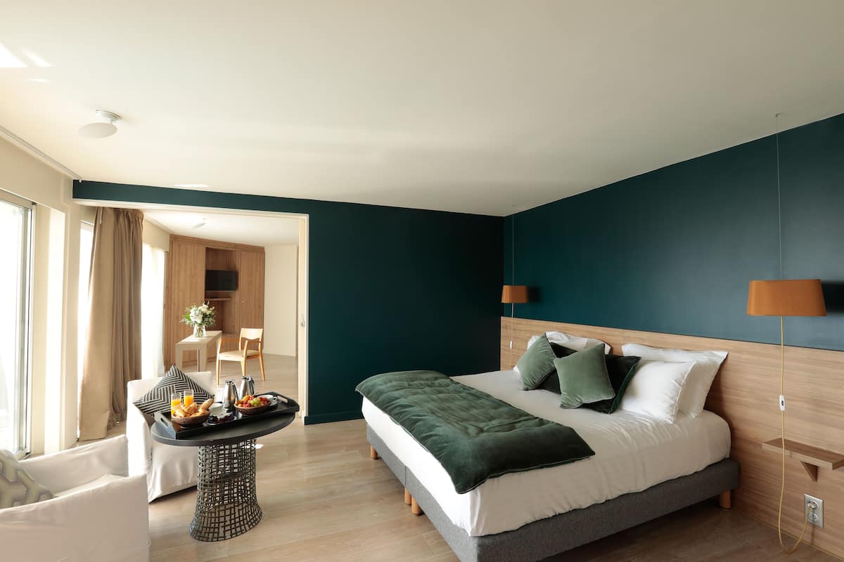 Een moderne slaapkamer met een bed, nachtkastje en uitzicht op een eetruimte.