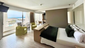 Een hotelkamer met balkon, bed, bureau en stoel.
