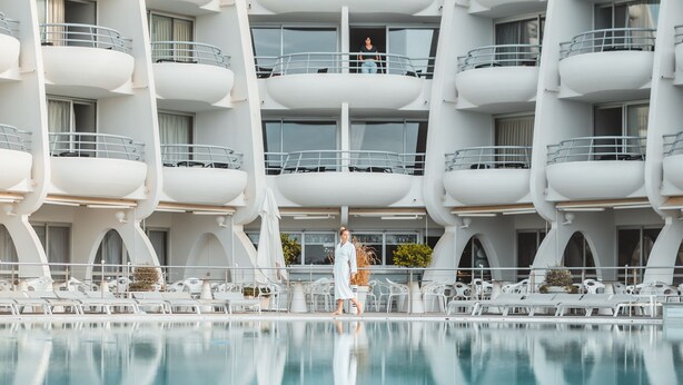 Een modern hotel met een zwembad op de voorgrond.