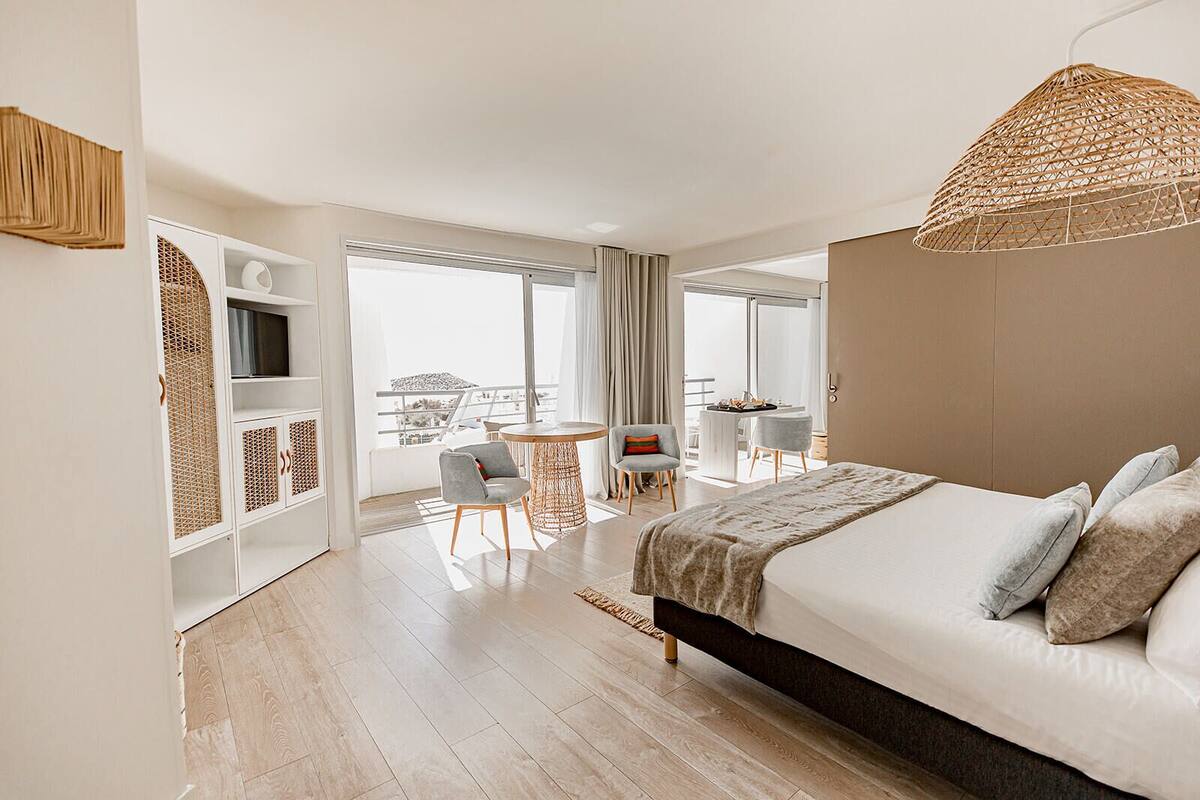 Een moderne hotelkamer met een groot bed, een zithoek en een balkon met uitzicht.