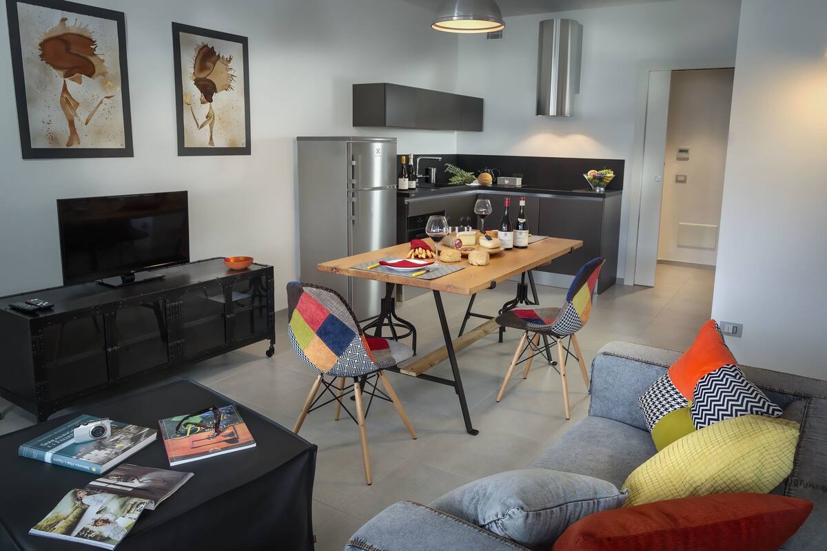A modern kitchen with a dining table, chairs, and a refrigerator.