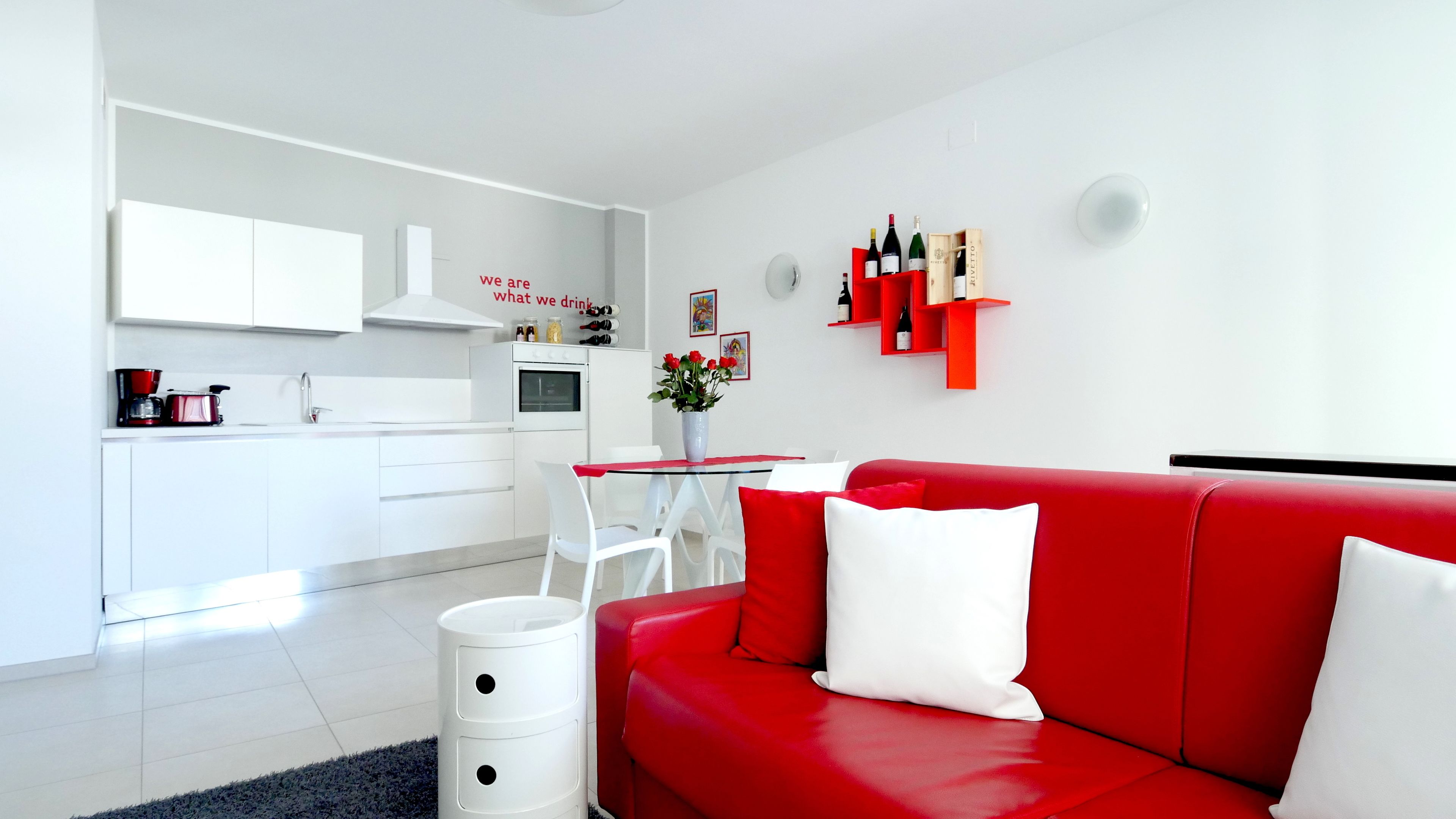 Un espace de vie moderne avec un canapé rouge, une table à manger blanche et un coin cuisine.