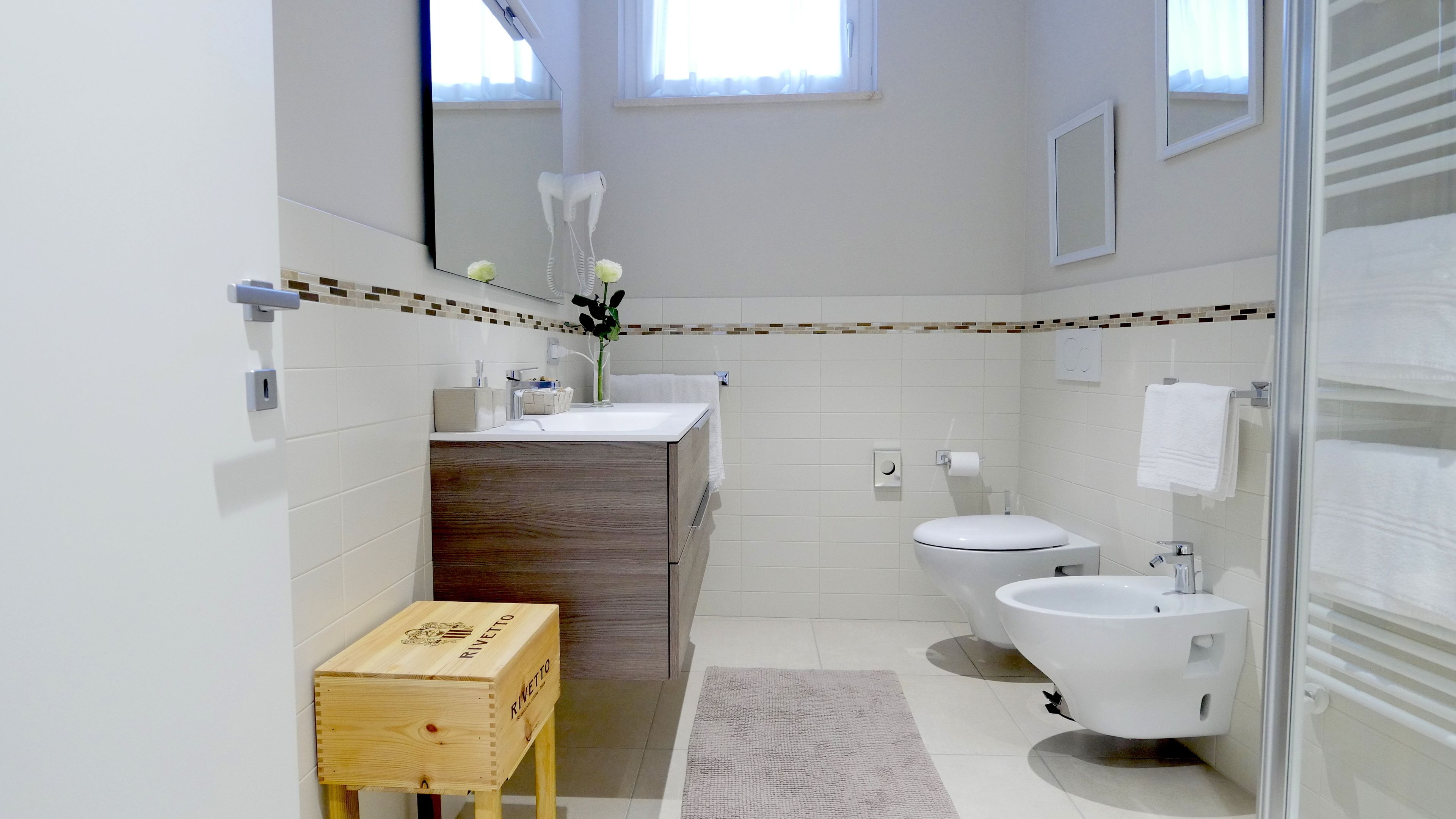 Ein modernes Badezimmer mit einem Holzlagerflansch, einem Bidet, einer Toilette und einem großen Spiegel.