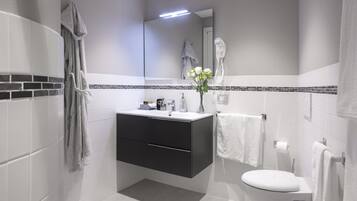 A modern bathroom with a white sink, dark cabinet, and a white toilet.