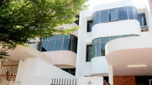 A modern building with multiple balconies, large windows, and a gated entrance.