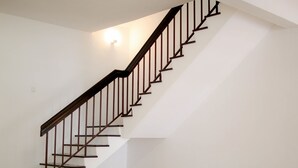 A staircase with a wooden handrail and metal balusters, leading to an upper floor.