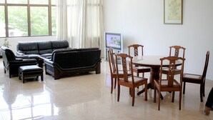A living room with a sofa, ottoman, and dining table with chairs.