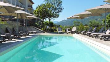 Relax by the serene pool surrounded by lush greenery and distant mountains.