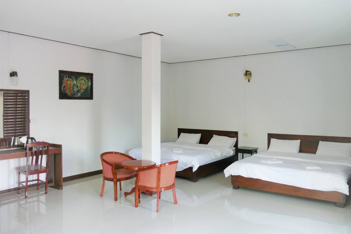 Una habitación de hotel con dos camas, un escritorio, una silla y un cuadro en la pared.