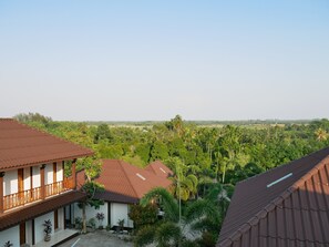 A residential area with houses featuring red roofs and white walls, surrounded by lush greenery and palm trees. - Pattana Resort (Klaeng)