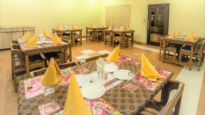 Comedor con varias mesas dispuestas para comidas, con servilletas amarillas y manteles florales.