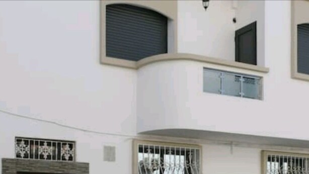 A multi-story building with large windows and a garage door. - Soleil d'Agadir Centre (Agadir)