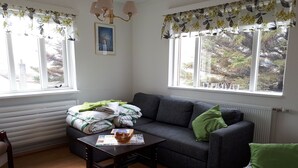 Un salon avec un canapé gris, une table basse en bois et une fenêtre avec des rideaux.