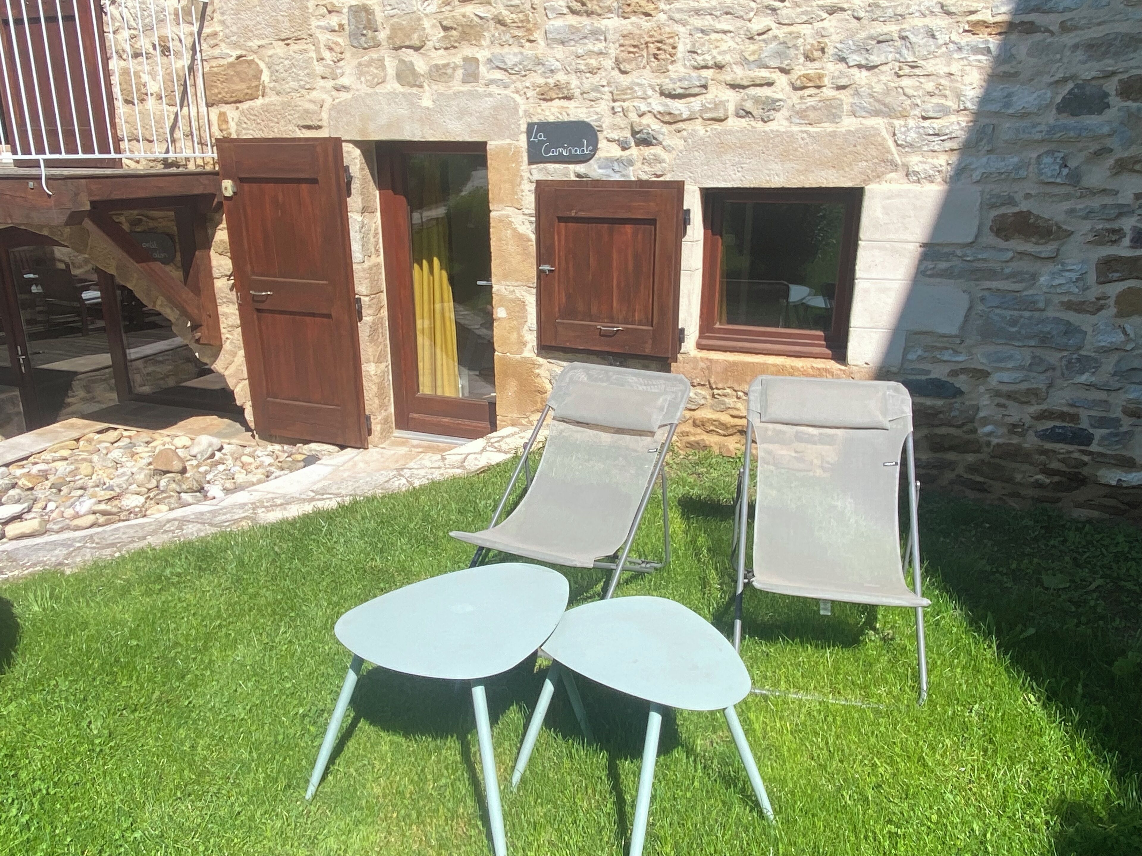 Een stenen gebouw met een bord waarop 'La Cariade' staat. Op de voorgrond staan twee metalen stoelen en een kleine tafel.