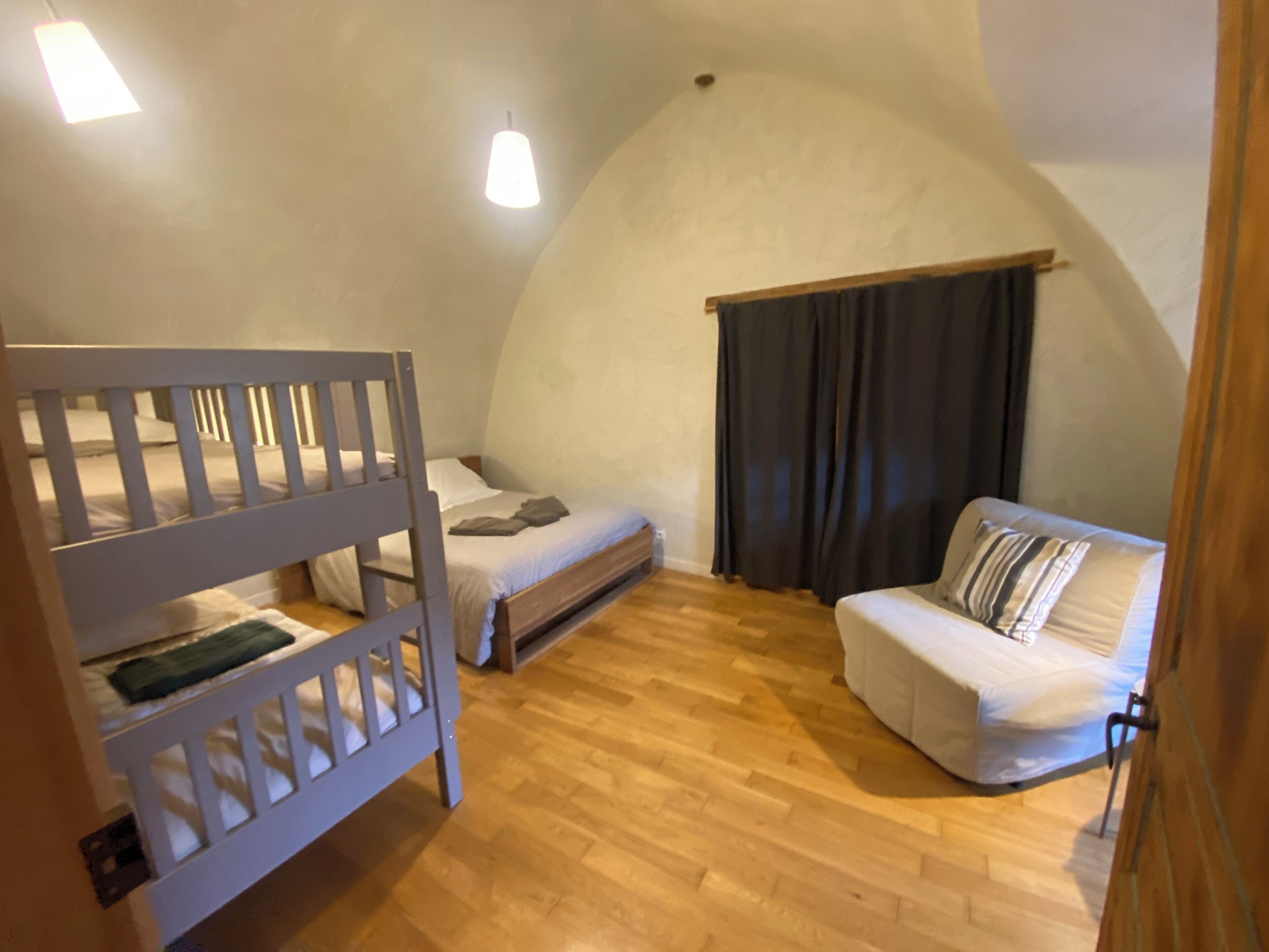 Una habitación acogedora con una cama litera, una cama individual y un sofá.