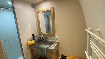 A small bathroom with a sink, mirror, and towel rack.