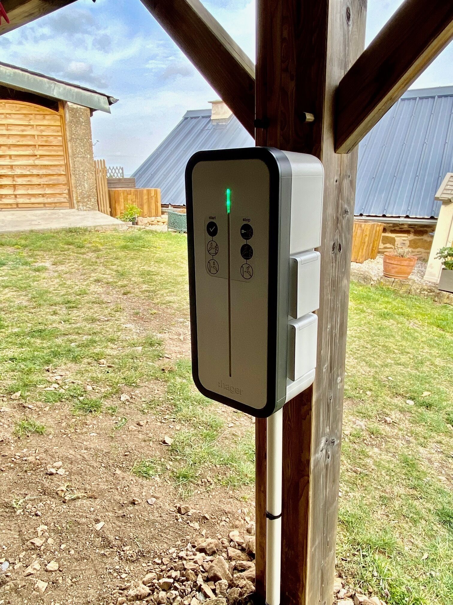 Une boîte de prise de courant fixée à un poteau en bois, dans un environnement extérieur.