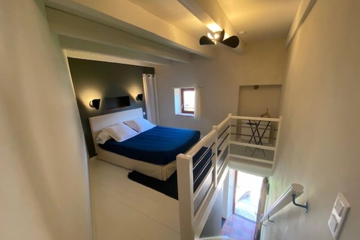 Quarto com cama, janela e escada.