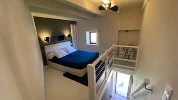 Ein Schlafzimmer mit einem Bett, einem Fenster und einer Treppe.