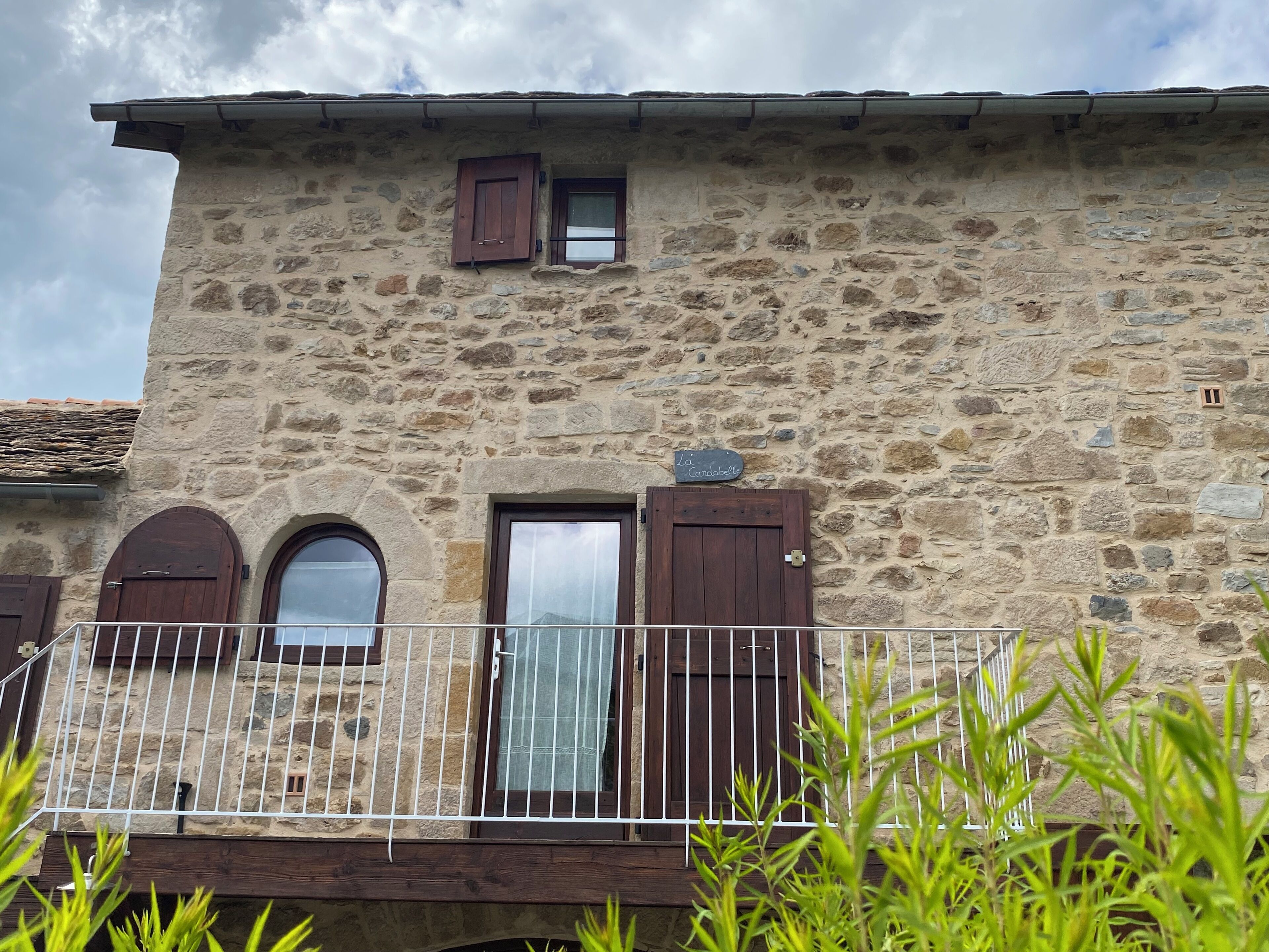 A stone building with a balcony, a door, and a window.