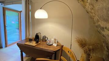 A cozy dining area with a wooden table, chairs, a coffee maker, cups, and a decorative vase.
