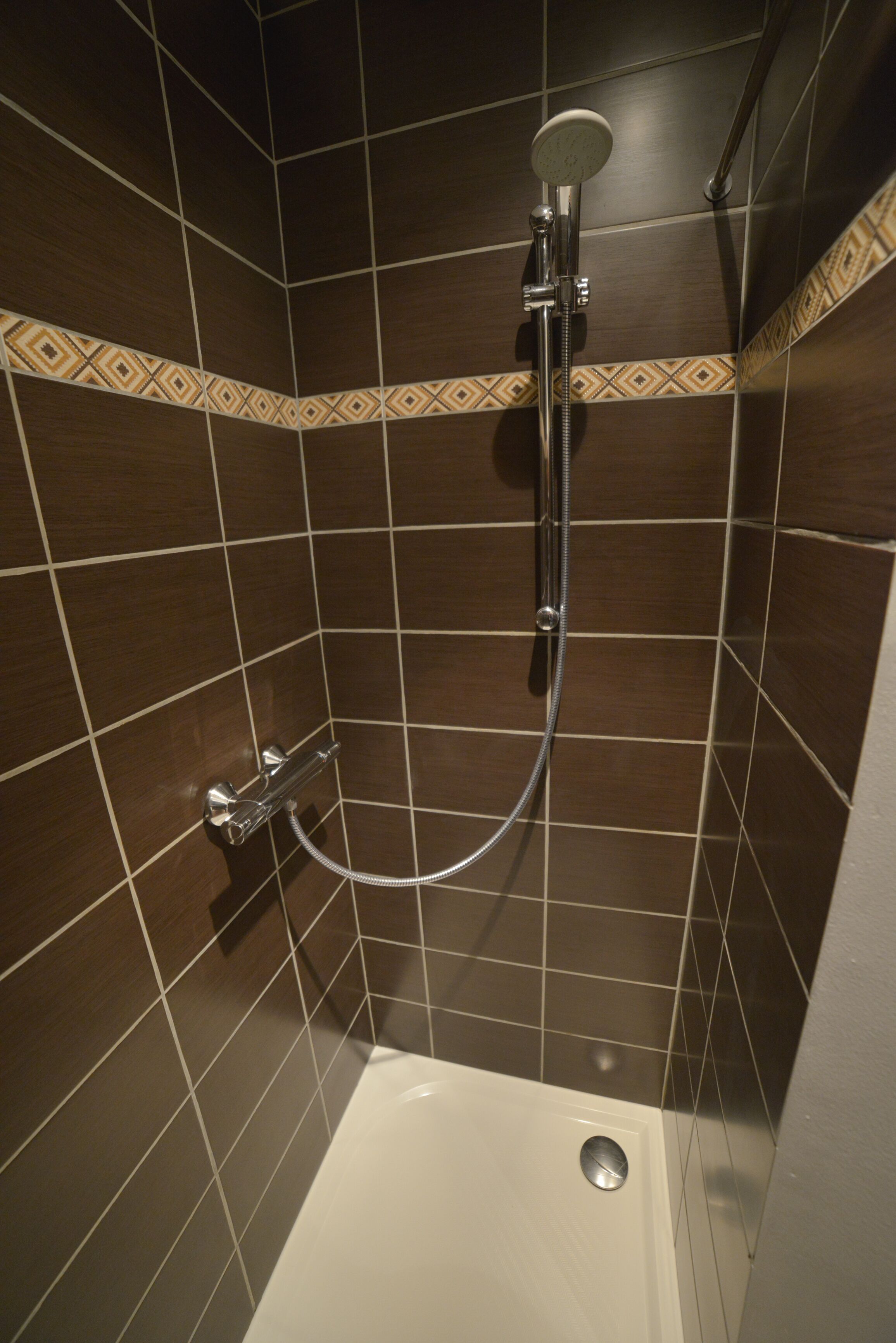 Un espace douche équipé d’un pommeau de douche à main, d’un robinet mural et d’un drain.