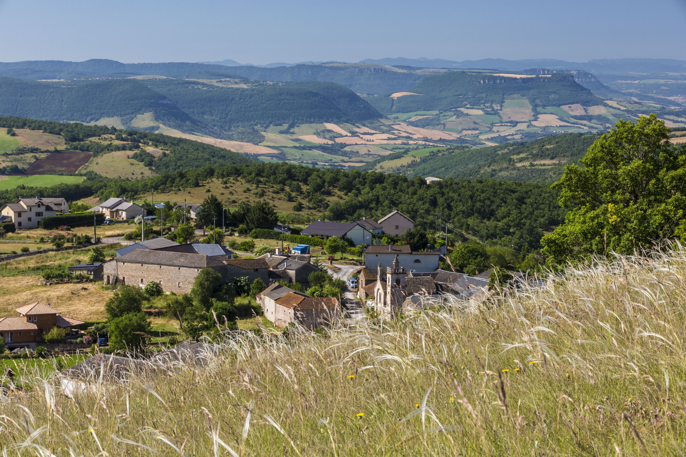 A rural village with houses, a church, and rolling hills in the background.