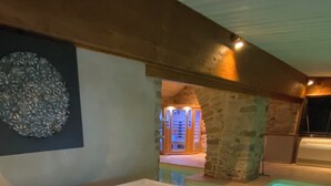 Un jacuzzi con luces LED azules, una pared de piedra y un techo de madera.