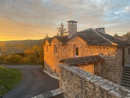 A stone building with a sloped roof, a chimney, and a small window.