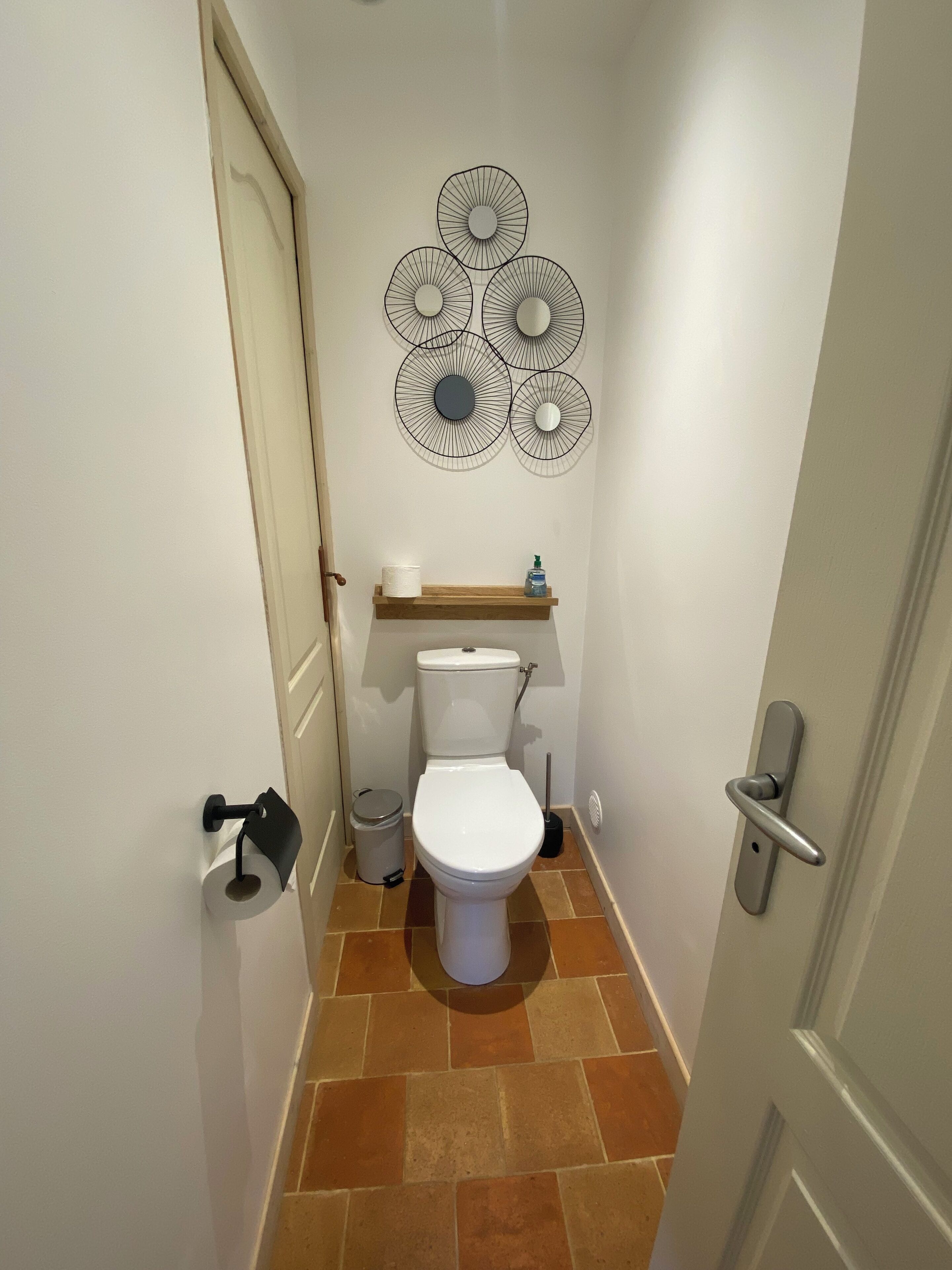 Un baño pequeño con inodoro, un cubo de basura y un dispensador de papel higiénico.