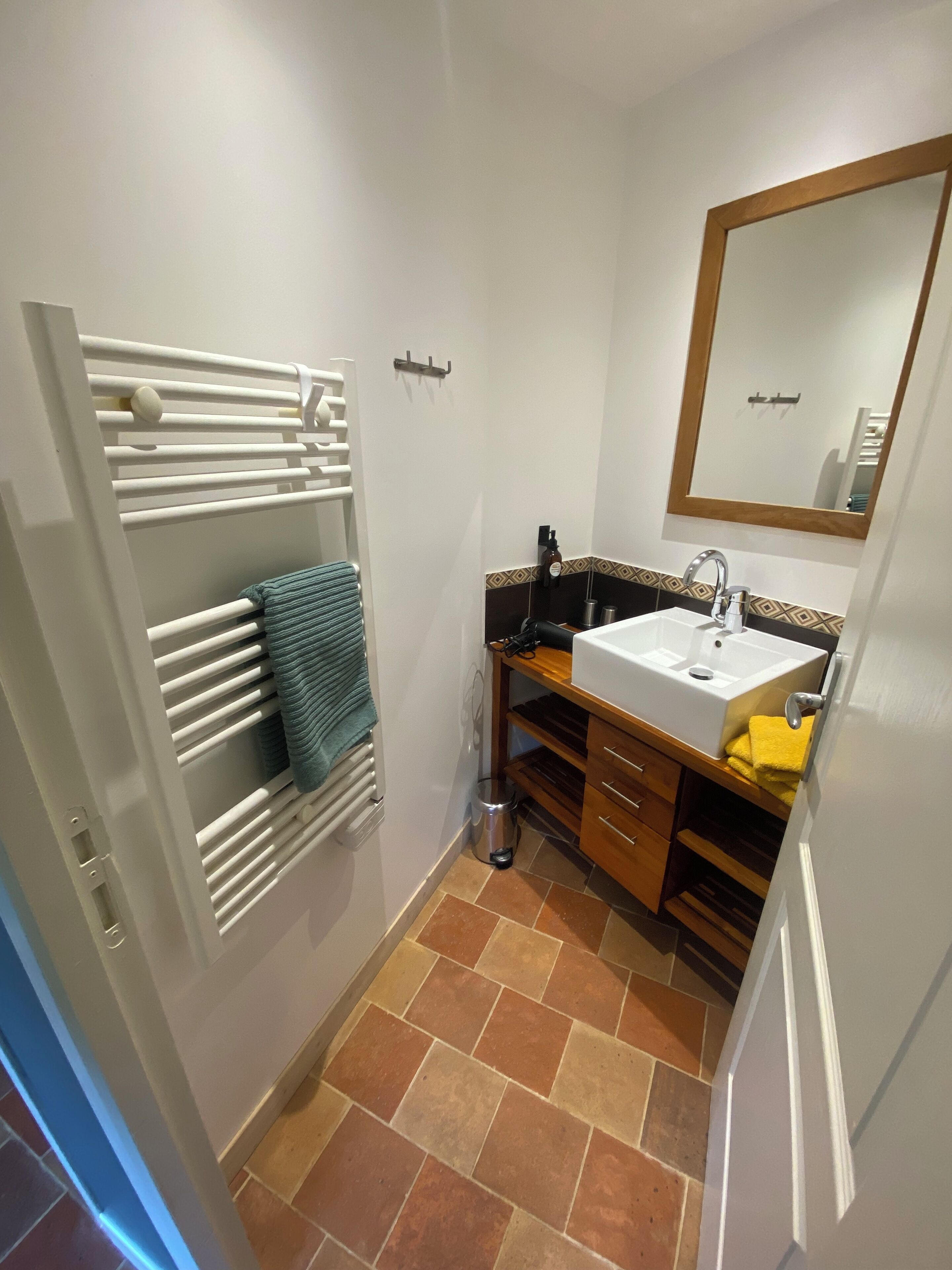 Un baño pequeño con un lavamanos blanco, un espejo y un perchero para toallas.