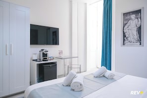 A hotel room with a bed, a desk with a coffee machine, a TV, and a statue. - Viale Giulio Cesare Guest House (Rome)