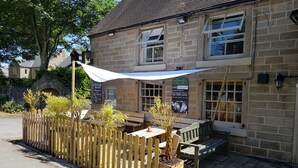 A stone building with a wooden fence, outdoor seating, and a sign advertising breakfast. - The Crown Inn (Alfreton)
