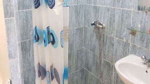 A bathroom with a shower, a sink, and a tiled wall. - Résidence Lumière (Abidjan)