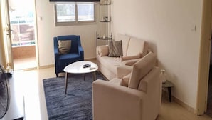 A living room with a sofa, armchairs, a coffee table, and a TV. - Résidence Lumière (Abidjan)