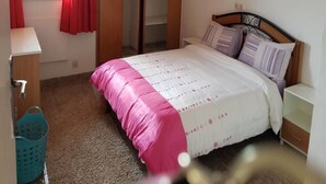 A bedroom with a bed, a wardrobe, a window with curtains, and a small bedside table. - Résidence Lumière (Abidjan)