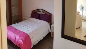 A bedroom with a bed, a wardrobe, a nightstand, and a mirror. - Résidence Lumière (Abidjan)